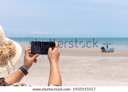 A young woman took a photo of a fishing boat parked by the beach.