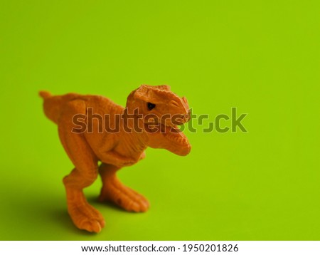 Isolated orange T-Rex dinosaur made from an eraser against a lime green background