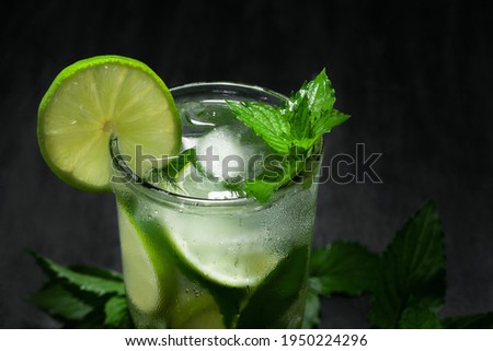 Fresh homemade mojito cocktail with lime, mint and ice on a black background, close-up, copy space