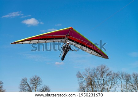 Learning to bly. Flying girl. Beginner pilot on a hang glider wing. Royalty-Free Stock Photo #1950231670