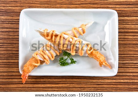 Shrimp tacos with burrito style chipotle chili dressing on white square plate over wood background