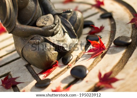 buddha statue with red leaves and massage stones
