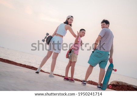 Family portrait, beach vacation, parents and children resting from skating, surfing, standing smiling happily.