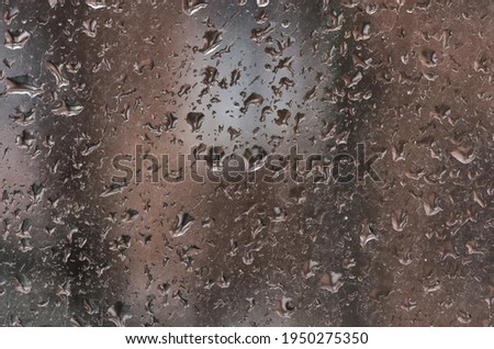 Raindrops on the surface of a dirty window glass. Rainy background with water drops on window glass