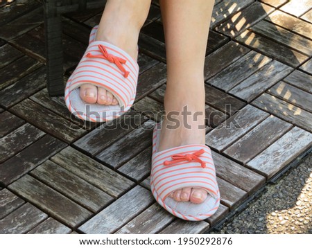 Photo of woman feet in summer slippers with patio background