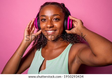 Black young woman indoor studio shot smiling positive and happy at camera wearing headphones