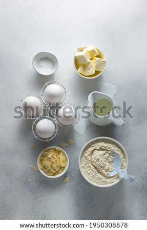 Baking ingredients - raw eggs, milk, soda, butter, flour, almond petals, top view