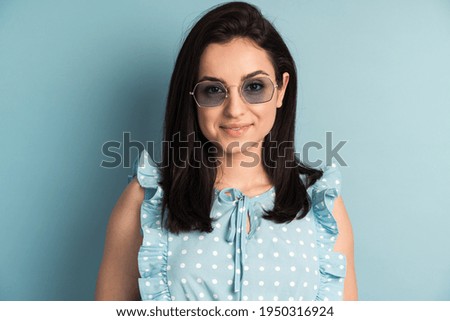 Close-up, portrait of an attractive young woman in sunglasses. Girl posing in the studio on a blue background.