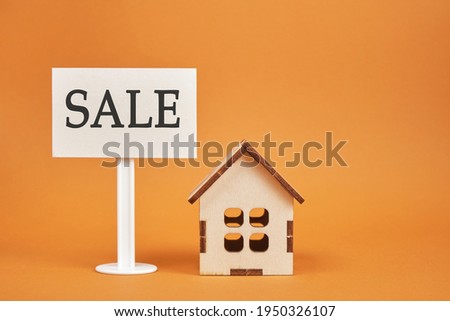 small wooden house model and white blank sign with the words sale on a brown background copy space house for sale