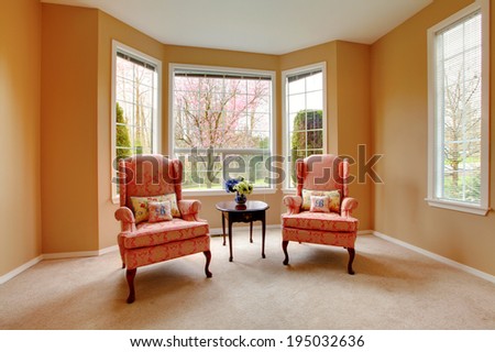 Furnished living room corner with antique pink chairs and dark brown table.
