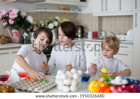 Children, boy siblings, coloring eggs for Easter at home