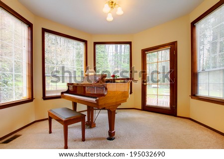 Peaceful room with antique piano and ottoman.