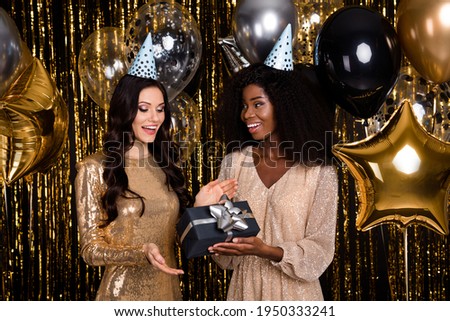 Photo of two glamour brunette girls give gift wear cone hat balloons party isolated on shine bright tinsel background