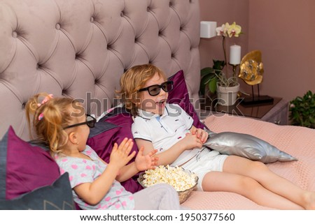 Happy children watching 3D movie with glasses and popcorn.