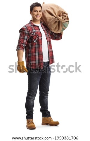 Full length portrait of a young farmer carrying a burlap sack on his shoulder isolated on white background
