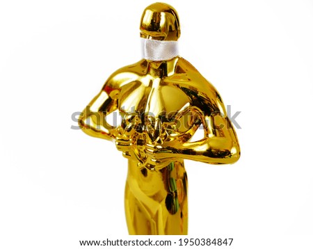 Hollywood Golden Oscar Academy award statue in mask aganist covid-19 isolated on white background. Success and victory concept. Oscar ceremony in coronavirus time