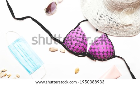 Summer holiday vacation and new normal concept, top view of stylish pink swimsuit and women's accessories with protective face mask