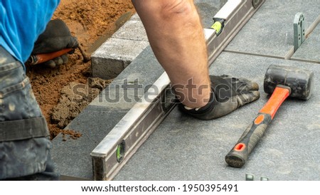 Expert workman laying patio edging bricks in garden makeover
