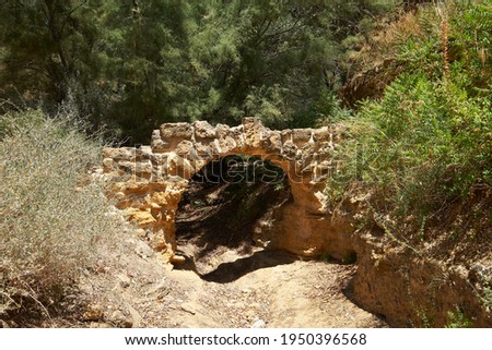 Kolymbethra Gardens, or Jardino della Kolymbethra. magnificent green garden in the heart of the Valley of Temples, Sicily, Italy. Stone arch over footpath and garden wall. Selective focus.