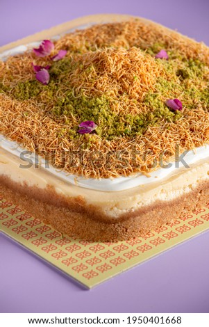 Kunafa Cheesecake with pistachio and flowers in top on purple background 