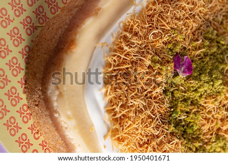 Kunafa Cheesecake with pistachio and flowers in top on purple background 