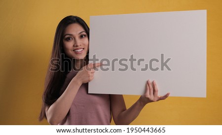 Young pretty woman holds a sign mock-up - studio photography