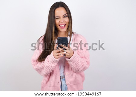 Young beautiful caucasian woman wearing pink knitted jacket over white wall taking a selfie  celebrating success