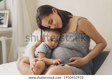 Young woman with her first child during second pregnancy. Motherhood and parenting concept. Toddler boy and mom. Happy family expecting for baby.  Royalty-Free Stock Photo #1950452932