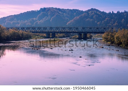 Panoramic view of mountain valley with river and railroad bridge in autumn during sunset. 