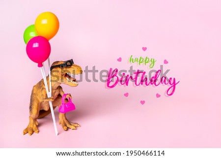 Toy dinosaur Tyrannosaurus with sunglasses holding colorful balloons, bag in its paws on pink background Holiday card Happy birthday creative minimal concept 