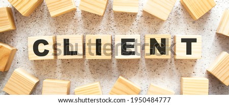 The word CLIENT consists of wooden cubes with letters, top view on a light background. Work space.