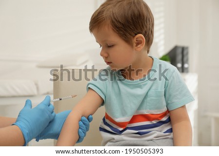 Nurse vaccinating little boy in clinic. Immunization concept