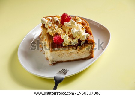 Toffee Popcorn Cheesecake  with raspberry and popcorn in the top on yellow background 