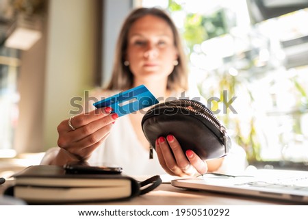 Beautiful blonde girl in a coffee shop holds a blue plastic card in her hand. .Focus on foreground