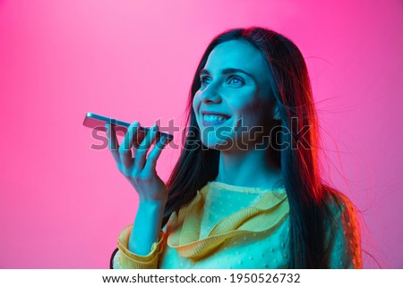 Young beautiful girl talking on phone isolated on pink background in neon light