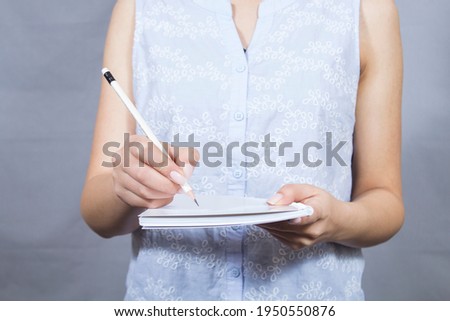 girl writes with a pencil on a notebook on a gray background