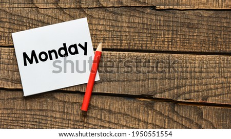 Monday written on a white piece of paper laid on a wooden table. 
