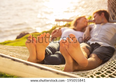 Romantic couple relaxing in tropical hammock at sunset, Shallow depth of field, focus on feet.