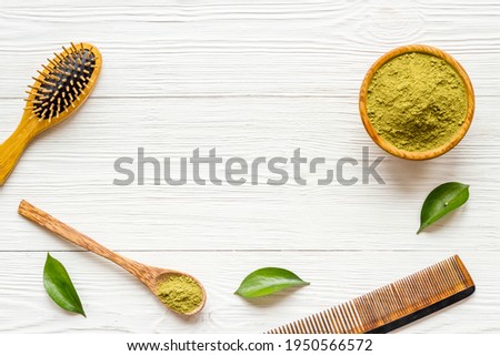 Henna powder in wooden bowl with green leaves. Herbal natural hair dye
