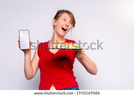 Happy girl received sushi after online delivery. The blonde holds sushi on a tray and a smartphone screen. White background with side blank space. High quality photo