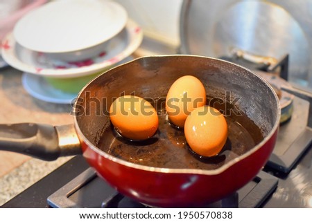 Eggs boiling in water on the gas stove with Sunlight. Picture have noise, Soft focus.
