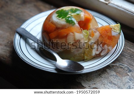 Close up of aspic made with chicken, eggs and vegetables carrots and parsley served on a white plate. Poland, Europe       