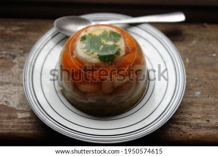 Close up of aspic made with chicken, eggs and vegetables carrots and parsley served on a white plate. Poland, Europe       