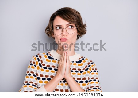 Portrait of attractive minded strict girl praying thinking asking luck isolated over grey pastel color background