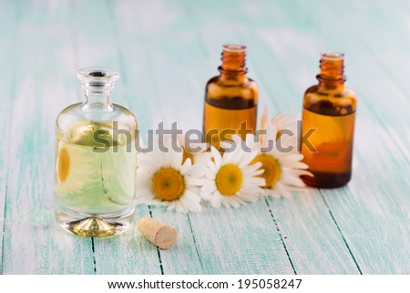 Essential aroma oil with chamomile on wooden background. Selective focus, horizontal.