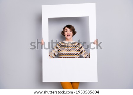 Portrait of lovely funny cheerful girl holding in hands big photo frame isolated over grey pastel color background