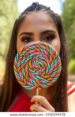 Beautiful brunette girl holding colorful lollipop in the forest. Selective focus