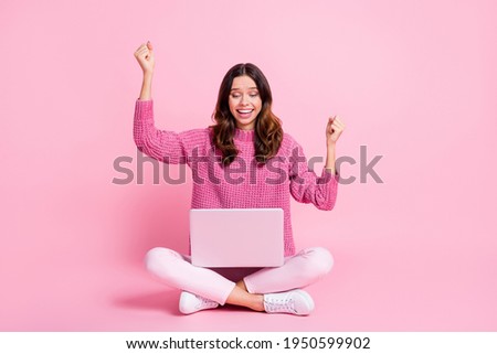 Full size photo of hooray nice brunette lady sit hands fists look laptop wear pink sweater trousers isolated on pink background