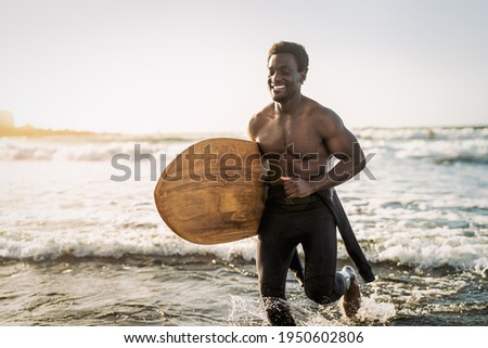 Male afro surfer having fun surfing during sunset time - African man enjoying surf day - Extreme sport lifestyle people concept  Royalty-Free Stock Photo #1950602806