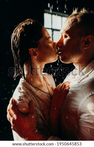 The guy hugs the girl. Water drops against background and on the people. Heterosexual couple lifestyle moments at home. Conceptual photo about heterosexuality Royalty-Free Stock Photo #1950645853